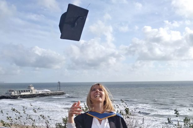 Nicola Shawyer on her graduation day, throwimg her mortar board high in the air and smiling